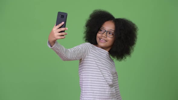 Young Cute African Girl with Afro Hair Using Phone alt