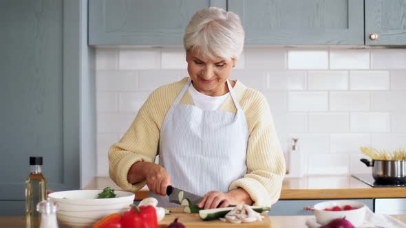 Happy Woman Chopping Zucchini on Kitchen