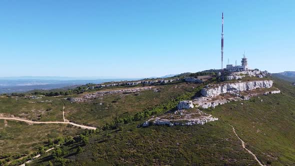 Drone Shot (rotating) of a Radio Station on top of an Arid Hill under a Midday Sun alt
