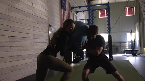 Couple training with exercise ball as they push towards each other