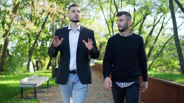 Front View Two Positive Young Men Talking Strolling in Sunny Spring Summer Park alt