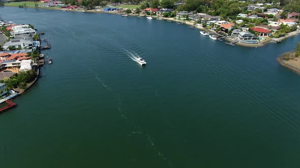 Drone footage,flying towards cruising boat in large canal, Calm summers day. Gold Coast alt