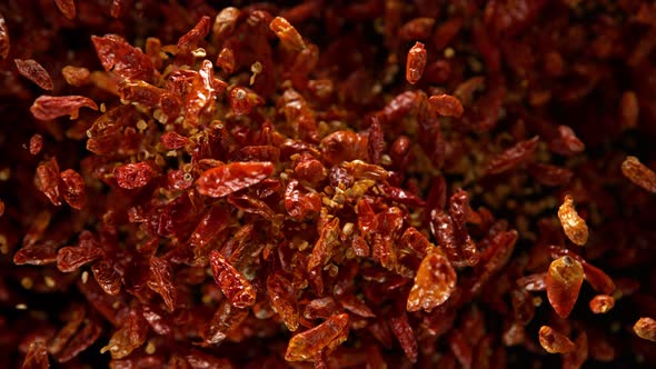 Super Slow Motion Shot of Dried Red Chili Peppers Explosion on Black Background at 1000Fps alt