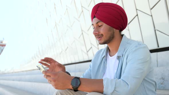 Hilarious Indian Man in Casual Shirt and Traditional Headwear Turban Using Smartphone