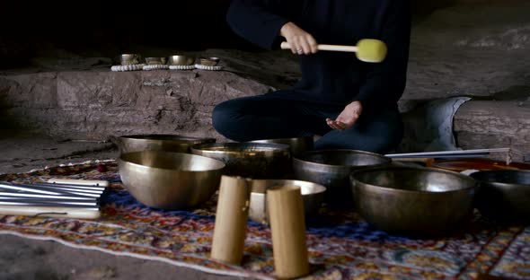 Serious Lady Hits Metal Bowls with Brown Wooden Hammer alt