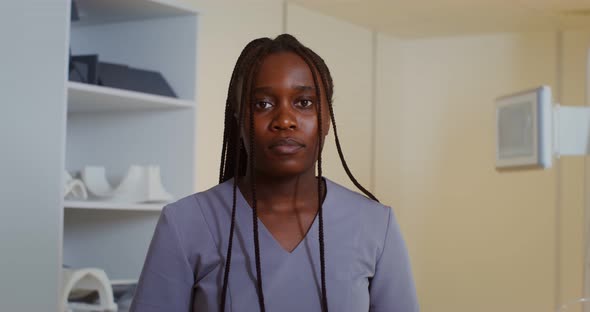 A Doctor Looks Into the Camera Standing in Front of an MRI Machine alt