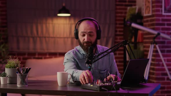 Portrait of Man Recording Podcast Using Audio Mixer and Laptop Computer Talking in Professional alt