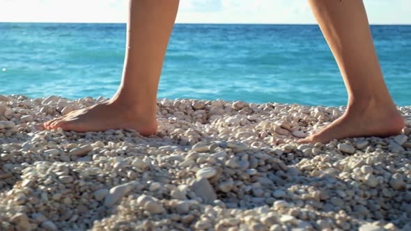 Closeup woman's legs walking on beach at sunset over a sea. Slow motion footage