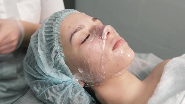 The Cosmetologist Removes the Gel and Food Film From the Client's Face