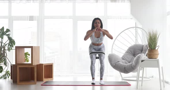 Sporty black woman is training at home in living room.