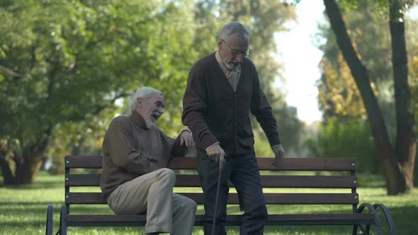 Aged Man Joking With Friend Kicking Butt, Friendship Humor, Having Fun, Leisure alt