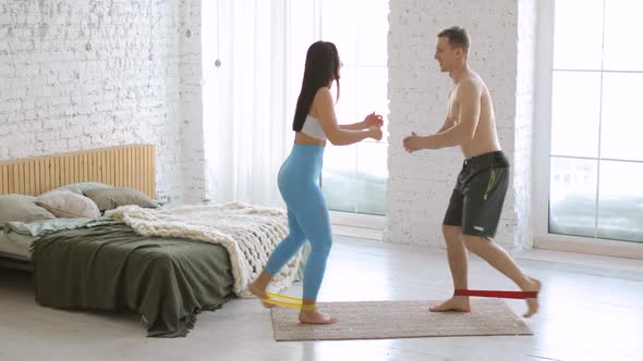 Woman and Man Are Training and Doing Lunges Exercise Using Rubber Bands at Home