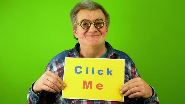 Caucasian Mature Adult Man Smiling and Point Finger at Plaque Lettering Click Me alt