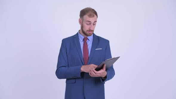Happy Bearded Businessman Reading on Clipboard and Giving Thumbs Up