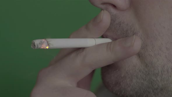 Cigarette in the Mouth of a Smoker. Close-up. Chroma Key. Green Background. alt