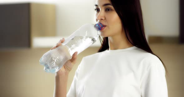 Brunette Drinks Mineral Sparkling Water From a Plastic Bottle