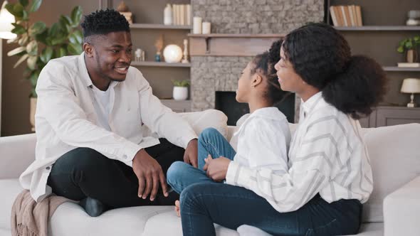 African Family Adult Parents and Schoolgirl Daughter Girl Child Sitting on Sofa at Home in Living alt