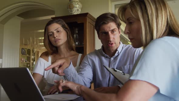 Caucasian couple and a senior Caucasian woman sitting on a couch in an apartment alt