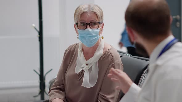 Senior Patient and Specialist with Face Masks Talking About Virus Prevention alt