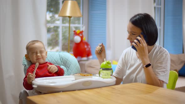 Busy Mother on Mobile Phone Feeding Baby at Same Time alt