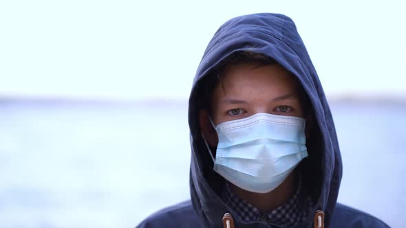 Boy Medical Mask on His Face During Quarantine Stands on Beach During the Second Wave Quarantine alt