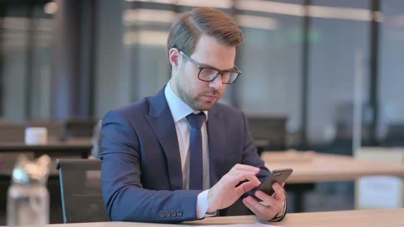 Businessman Browsing Internet on Smartphone in Office alt