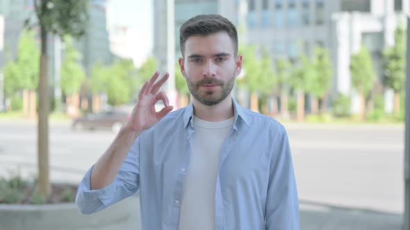 Outdoor Portrait of Young Man with Ok Sign alt