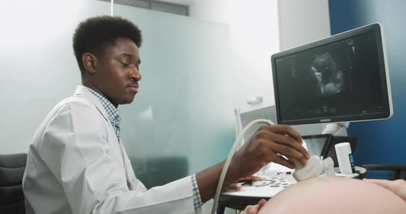 Young Professional Male African Doctor Looking at the Screen While Performing alt