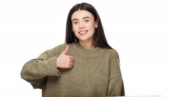 Portrait of Adorable Woman 20s with Long Dark Hair Expressing Approval with Gesturing Thumb Up Over alt