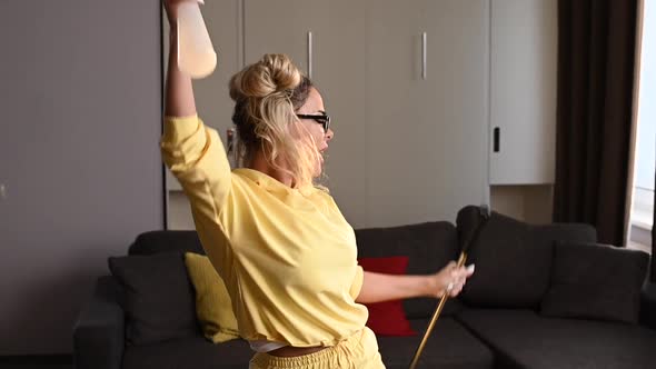 Happy Young Lady Is Washing Floor with Mop and Dancing at Home alt