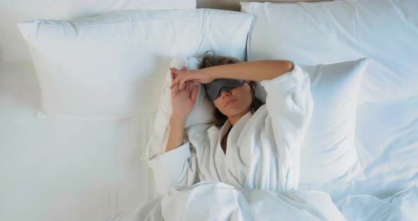 Attractive Woman Awakes and Takes Off Blindfold on Large Bed