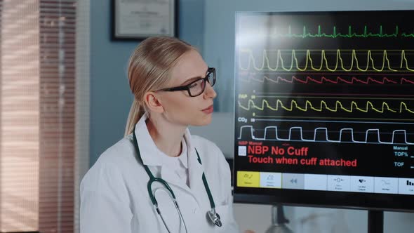 Closeup of Smart Female Cardiologist in Lab Coat Discussing EKG Data with Colleague alt
