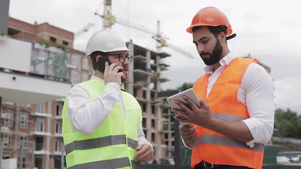 Engineer Speaks on Mobile Phone on Construction Site and Checks the Work of the Worker. Builder alt