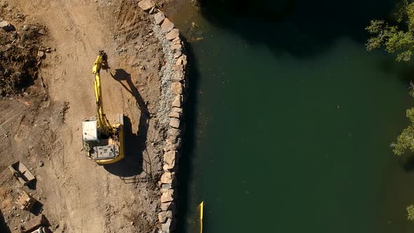 A large excavator repairing a section of river damaged by a flood waters caused by a tropical cyclon alt