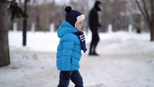 Boy Walks in Snowy Street