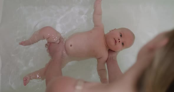Top View of Funny Newborn Baby Swimming During Bathing with Mother's Help alt