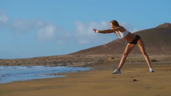 Woman Stretching Legs and Hamstrings Doing Standing Forward Bend Yoga Stretch Pose on Beach alt