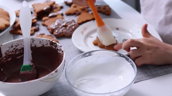 The Kid's Hands Applies White Icing Onto Xmas Cookies By Culinary Brush