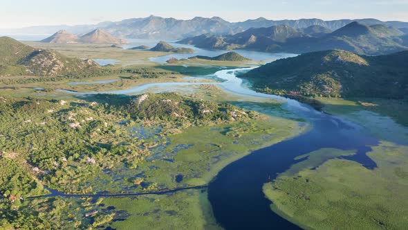 Bends and curves of blue river flowing through green valley toward distant mountains. alt