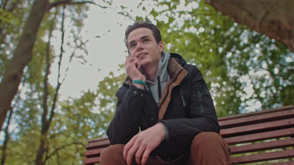 Handsome Man Teenager Talking on the Phone Slow Motion Positive Park Green Trees alt