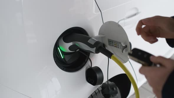 Woman Unlocked an Electric Car Using a Key and Unplugging the Cable From Electric Vehicle alt