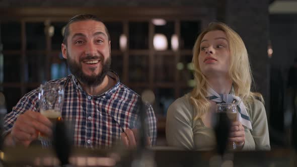 Front View of Happy Sports Fans Rejoicing Victory at Bar Counter Talking Smiling Toasting Clinking alt