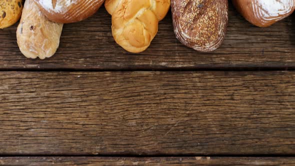 Various bread loaves arranged on wooden background alt