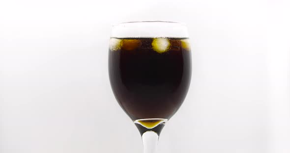 ice cube falls into an isolated cola drink glass