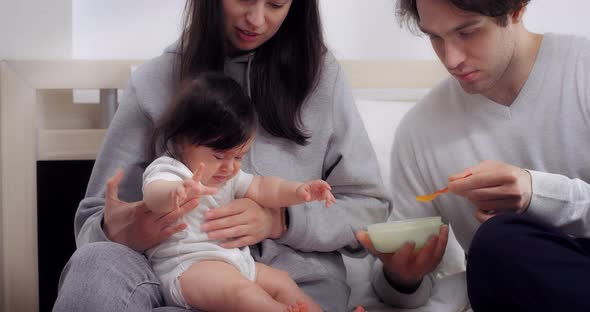 Crying Baby Wants to Eat Parents Feed Her Vegetable Puree with a Spoon