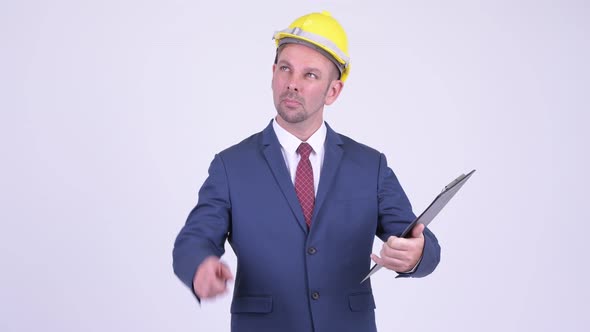 Happy Businessman As Engineer Holding Clipboard and Pointing Finger alt