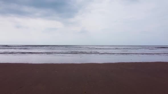 Drone shot of North sea beach. Empty beach with waves crashing. alt