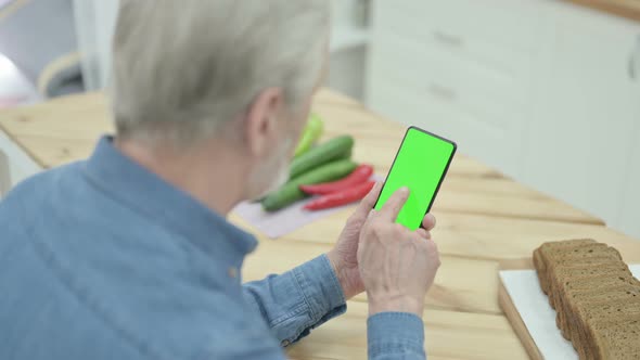 Rear View of Old Man Looking at Smartphone with Chroma Key Screen alt