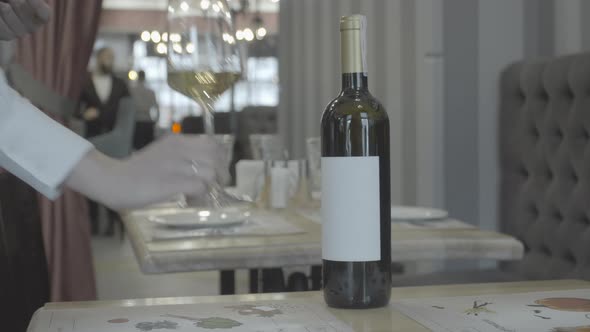 the hand of the waiter puts a glass of wine on the table in the restaurant. 4k