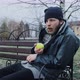 Hungry Bearded Homeless Man Sits on a Bench and Eats a Green Apple in a City Park - VideoHive Item for Sale